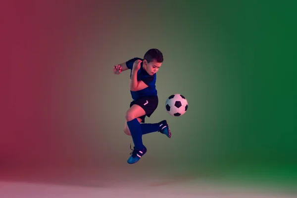 Adolescente futebol masculino ou jogador de futebol, menino em fundo gradiente em luz de néon - movimento, ação, conceito de atividade — Fotografia de Stock