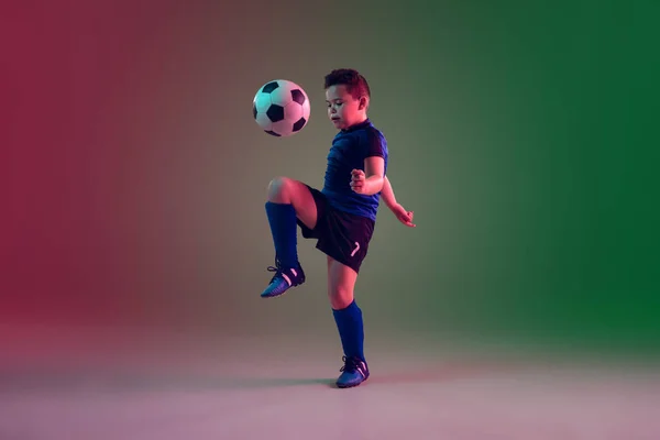 Giocatore di calcio o calcio maschile adolescente, ragazzo su sfondo sfumato in luce al neon movimento, azione, concetto di attività — Foto Stock