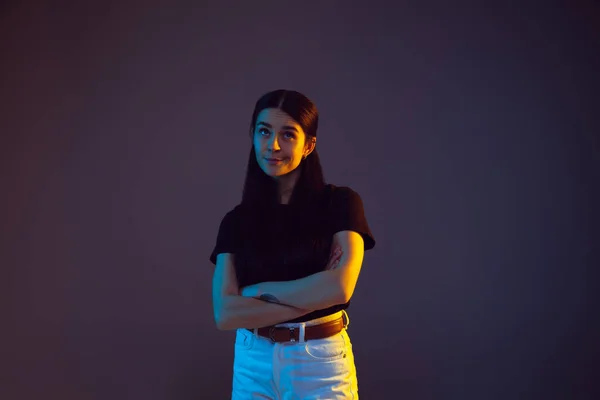 Wanita muda kaukasia potret pada latar belakang gelap dalam cahaya neon — Stok Foto