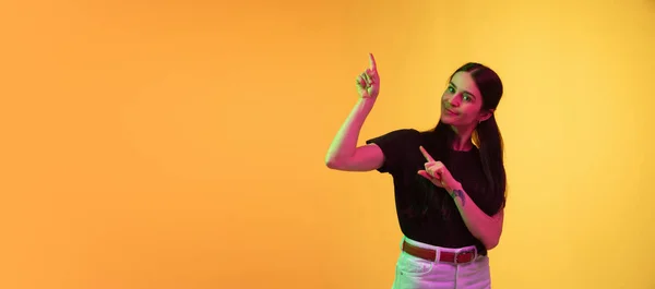 Mujeres jóvenes caucásicas retrato sobre fondo amarillo en luz de neón — Foto de Stock