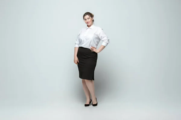 Junge kaukasische Frau in Bürokleidung auf grauem Hintergrund. Körperpositiver weiblicher Charakter. Plus-Size-Geschäftsfrau — Stockfoto
