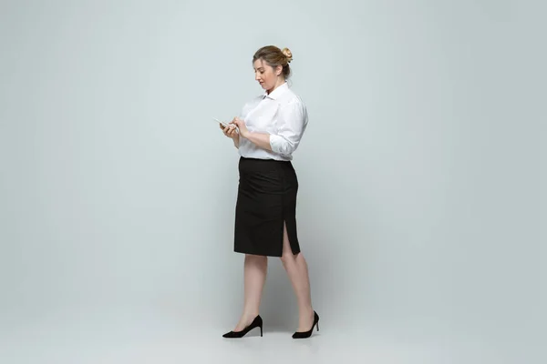 Mujer joven caucásica en traje de oficina sobre fondo gris. Personaje femenino positivo. más tamaño mujer de negocios — Foto de Stock