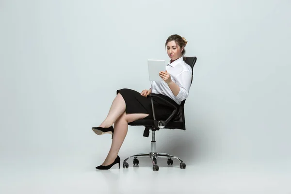 Молодая кавказка в офисной одежде на сером фоне. Тело положительный женский характер. плюс размер бизнесвумен — стоковое фото