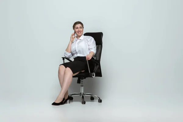 Mujer joven caucásica en traje de oficina sobre fondo gris. Personaje femenino positivo. más tamaño mujer de negocios — Foto de Stock