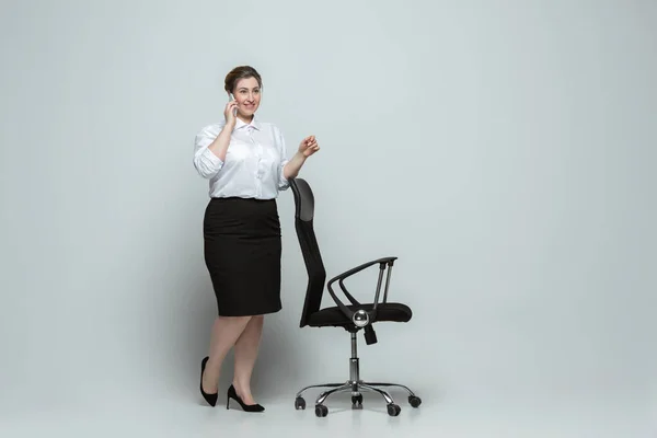 Mujer joven caucásica en traje de oficina sobre fondo gris. Personaje femenino positivo. más tamaño mujer de negocios — Foto de Stock