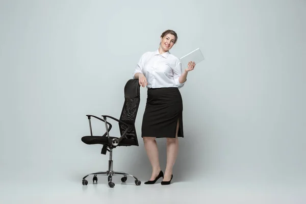 Mujer joven caucásica en traje de oficina sobre fondo gris. Personaje femenino positivo. más tamaño mujer de negocios — Foto de Stock