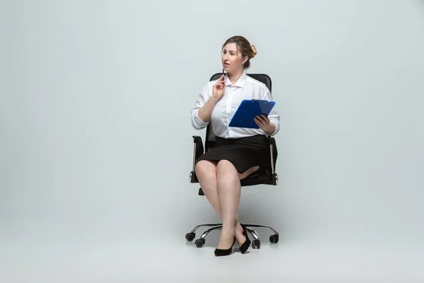 Mujer joven caucásica en traje de oficina sobre fondo gris. Personaje femenino positivo. más tamaño mujer de negocios — Foto de Stock