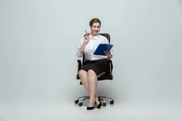 Mujer joven caucásica en traje de oficina sobre fondo gris. Personaje femenino positivo. más tamaño mujer de negocios — Foto de Stock