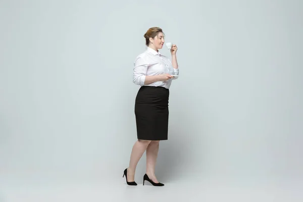 Mujer joven caucásica en traje de oficina sobre fondo gris. Personaje femenino positivo. más tamaño mujer de negocios — Foto de Stock