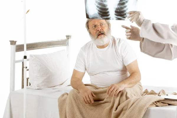 Літній літній чоловік, який відновлюється в лікарняному ліжку ізольовано на білому — стокове фото