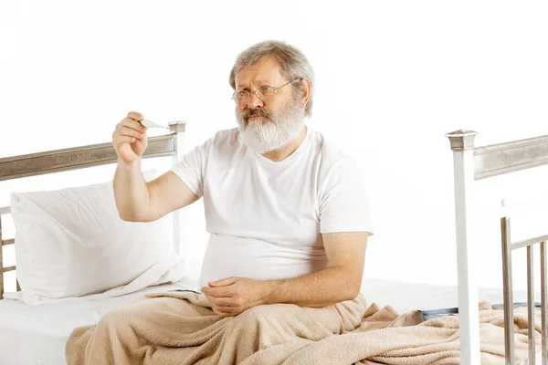 Elderly old man recovering in a hospital bed isolated on white