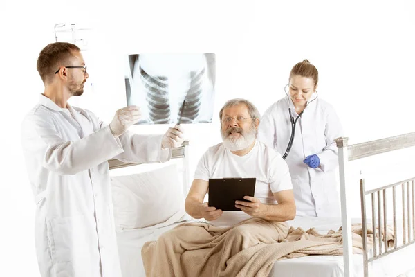 Elderly old man recovering in a hospital bed isolated on white