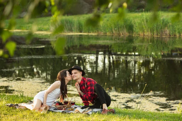 Kaukasiska unga och lyckliga par njuter av en picknick i parken på sommardagen — Stockfoto