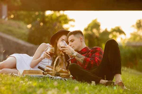 Kaukasiska unga och lyckliga par njuter av en picknick i parken på sommardagen — Stockfoto