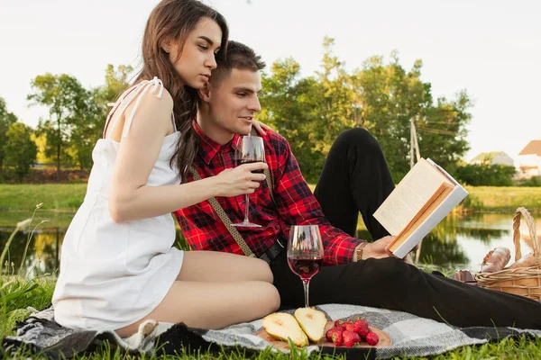 Caucásico joven y feliz pareja disfrutando de un picnic en el parque en el día de verano —  Fotos de Stock