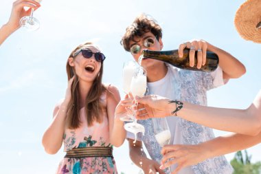 Plaj tatil köyünde mevsimlik ziyafet. Kutlama yapan, dinlenen, güneşli yaz gününde sahilde eğlenen bir grup arkadaş.