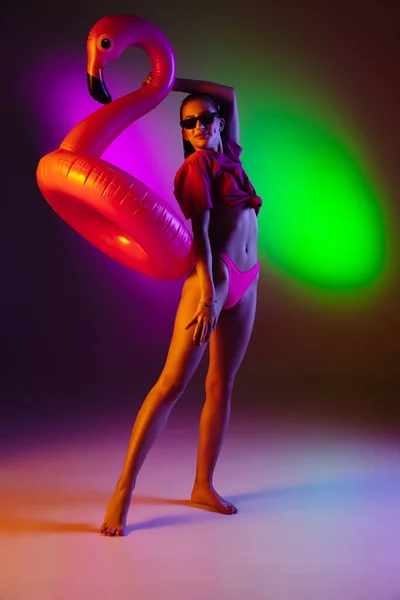 Belle fille séduisante en maillot de bain à la mode sur fond studio néon bicolore disco en lumière au néon. Été, station balnéaire, mode et concept week-end — Photo