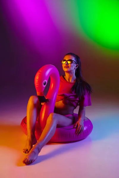 Schöne verführerische Mädchen in modischen Badeanzug auf Disco zweifarbigen Neon-Studio Hintergrund in Neonlicht. Sommer, Resort, Mode und Wochenendkonzept — Stockfoto