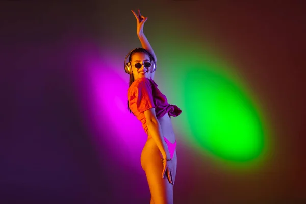 Menina sedutora bonita em maiô na moda na discoteca bicolor neon studio fundo em luz de néon. Verão, resort, moda e conceito de fim de semana — Fotografia de Stock