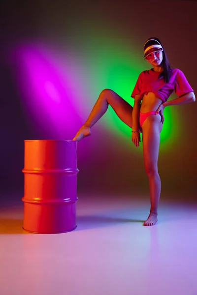 Krásná svůdná dívka v módních plavkách na diskotéce bicolored neon studio pozadí v neonovém světle. Léto, resort, módní a víkendový koncept — Stock fotografie