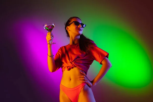 Menina sedutora bonita em maiô na moda na discoteca bicolor neon studio fundo em luz de néon. Verão, resort, moda e conceito de fim de semana — Fotografia de Stock