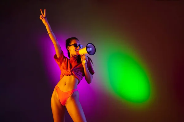 Schöne verführerische Mädchen in modischen Badeanzug auf Disco zweifarbigen Neon-Studio Hintergrund in Neonlicht. Sommer, Resort, Mode und Wochenendkonzept — Stockfoto