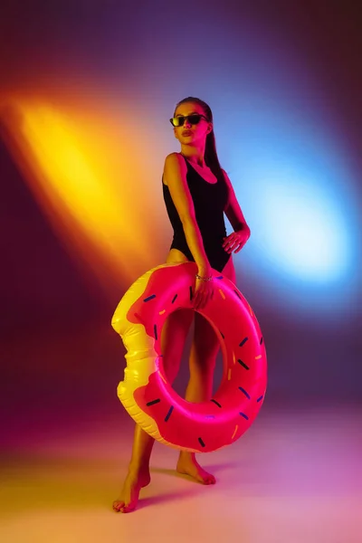 Menina sedutora bonita em maiô na moda na discoteca bicolor neon studio fundo em luz de néon. Verão, resort, moda e conceito de fim de semana — Fotografia de Stock