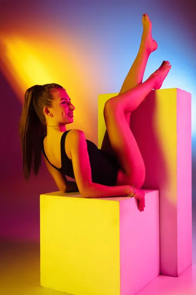Belle fille séduisante en maillot de bain à la mode sur fond studio néon bicolore disco en lumière au néon. Été, station balnéaire, mode et concept week-end — Photo
