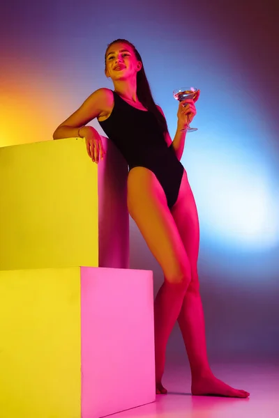Красива спокуслива дівчина в модному купальнику на дискотечному фоні неонової студії в неоновому світлі. Літо, курорт, мода і концепція вихідних — стокове фото