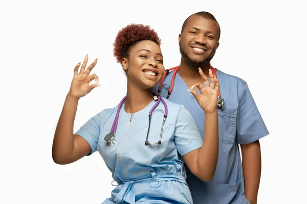 Un par de bellos médicos o enfermeras afroamericanos sonriendo aislados sobre el fondo blanco del estudio —  Fotos de Stock