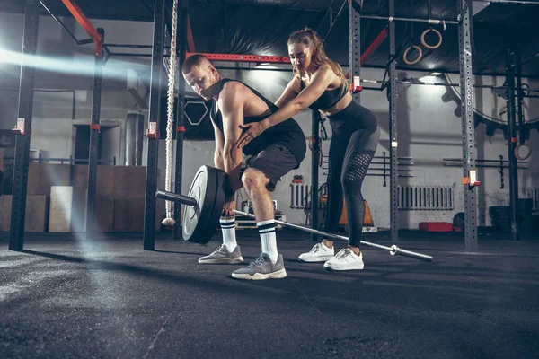 Hermosa joven pareja deportiva de entrenamiento, entrenamiento en el gimnasio juntos — Foto de Stock