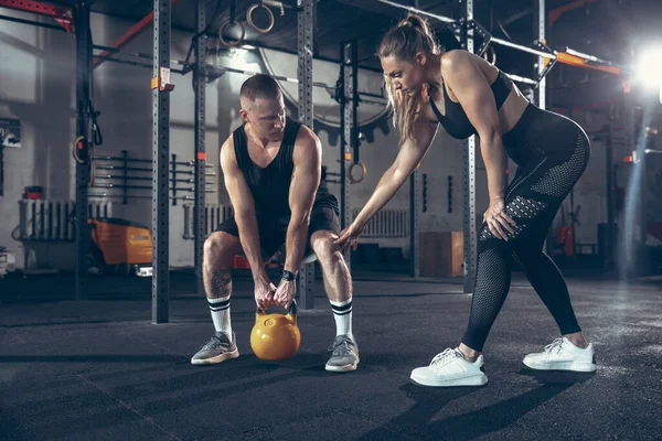 Hermosa joven pareja deportiva de entrenamiento, entrenamiento en el gimnasio juntos — Foto de Stock