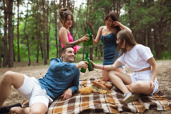 Group of friends clinking beer bottles during picnic in summer forest. Lifestyle, friendship — Stock Photo, Image