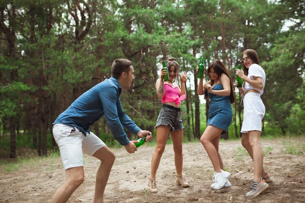 Group of friends walking down together during picnic in summer forest. Lifestyle, friendship