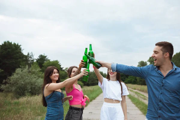 Grup de prieteni agățând sticle de bere în timpul picnicului în pădurea de vară. Stil de viață, prietenie — Fotografie, imagine de stoc