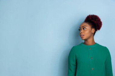 Mavi stüdyo arka planında Afro-Amerikan güzel genç kadın portresi, duygusal ve anlamlı. Reklam için kopyalama alanı.