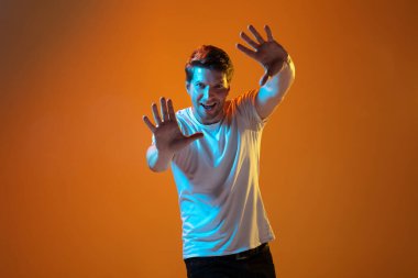 Beyaz tenli güzel genç adam portresi gradyan turuncu stüdyo arka planında, duygusal ve anlamlı. Reklam için kopyalama alanı.