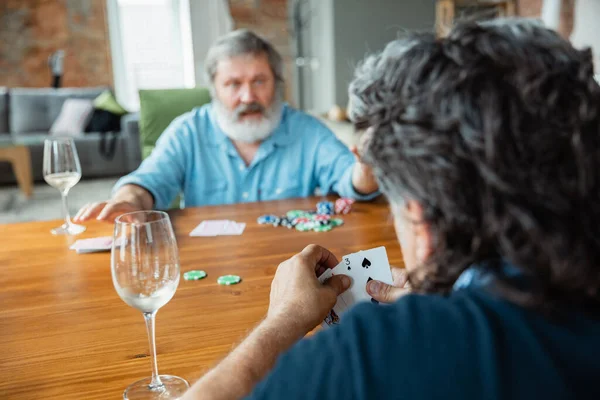 Two happy mature friends playing cards and drinking wine — Stock Photo, Image