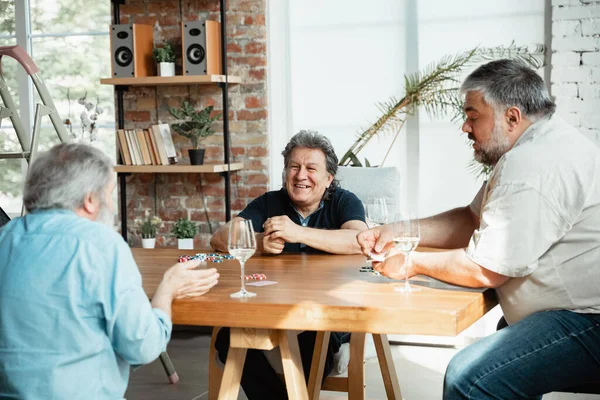 Group of happy mature friends playing cards and drinking wine — Stock Photo, Image