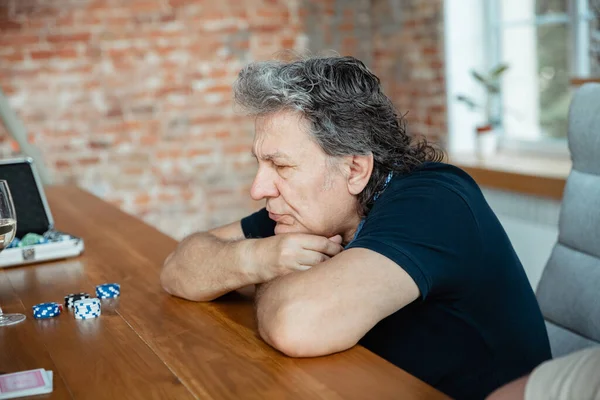 Senior man playing cards and drinking wine with friends, looks happy — Stock Photo, Image