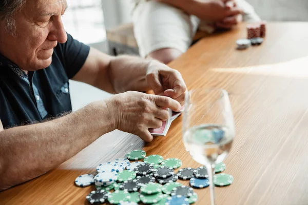 Senior man playing cards and drinking wine with friends, looks happy — Stock Photo, Image