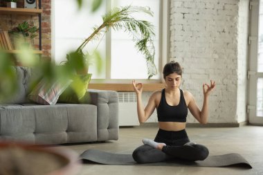 Sportif genç Müslüman kadın internette yoga dersleri alıyor ve evde pratik yapıyor.