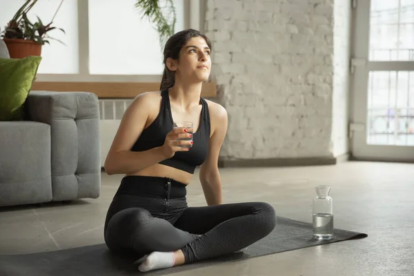 Sportieve jonge moslim vrouw die online yoga lessen neemt en thuis oefent — Stockfoto