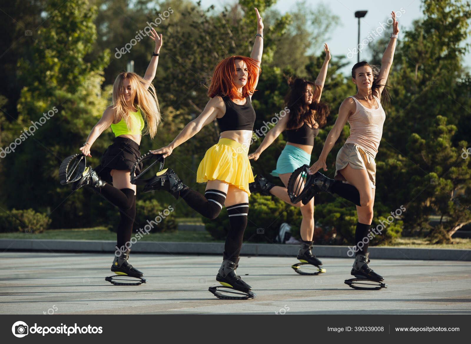 Close up women in sportswear jumping in a kangoo jumps shoes at the street  on summer's sunny day. Jumping high, active movement, action, fitness and  wellness. Fit female models during training. Photos