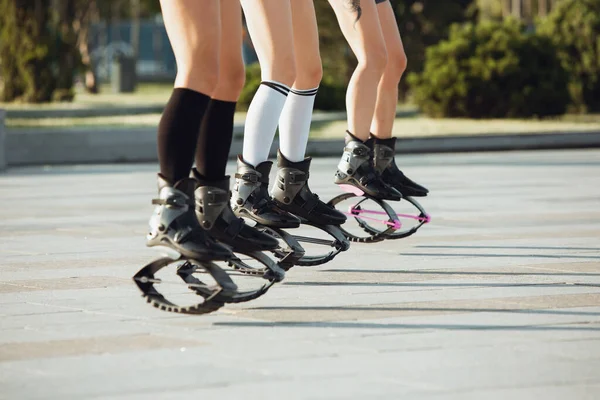 Beautiful women in sportswear jumping in a kangoo jumps shoes at the street on summers sunny day — Stock Photo, Image
