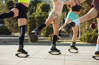 Spor giyim kuşamında güzel kadınlar kangoya atlayıp güneşli yaz günlerinde sokakta ayakkabı değiştiriyor.