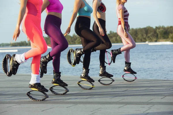 Hermosas mujeres en ropa deportiva saltando en un kangoo salta zapatos en la calle en los veranos día soleado —  Fotos de Stock