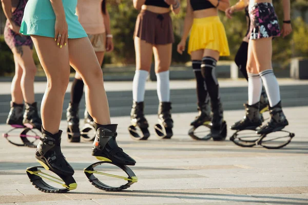 Hermosas mujeres en ropa deportiva saltando en un kangoo salta zapatos en la calle en los veranos día soleado —  Fotos de Stock