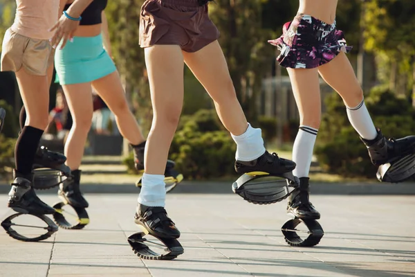 Hermosas mujeres en ropa deportiva saltando en un kangoo salta zapatos en la calle en los veranos día soleado — Foto de Stock