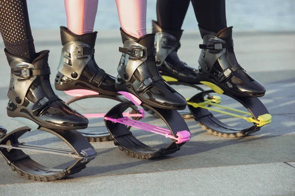 Hermosas mujeres en ropa deportiva saltando en un kangoo salta zapatos en la calle en los veranos día soleado —  Fotos de Stock